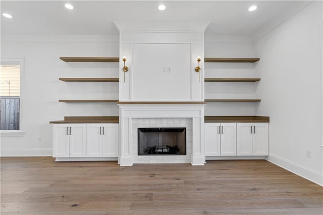 unfurnished living room featuring ornamental molding, light hardwood / wood-style floors, and a fireplace