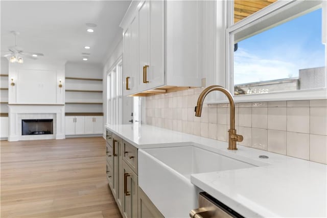 kitchen with a healthy amount of sunlight, white cabinets, light hardwood / wood-style floors, and backsplash