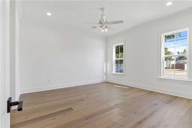 empty room featuring a wealth of natural light, hardwood / wood-style flooring, and crown molding