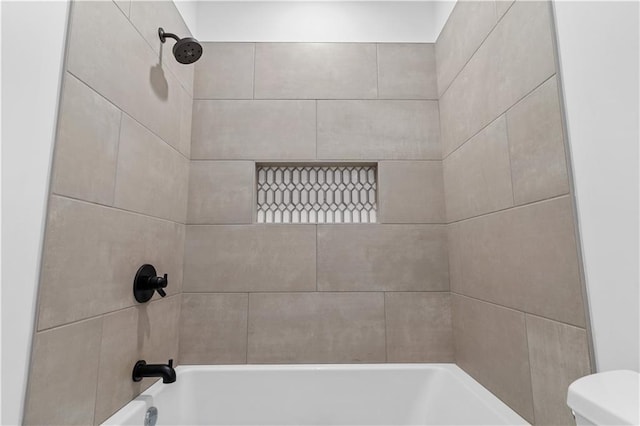 bathroom with tiled shower / bath combo and toilet