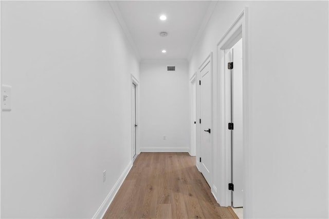 hallway with light hardwood / wood-style floors and ornamental molding