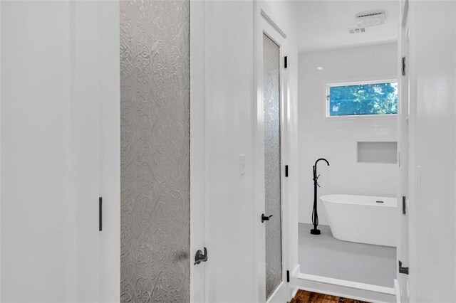 bathroom with a tub and hardwood / wood-style floors