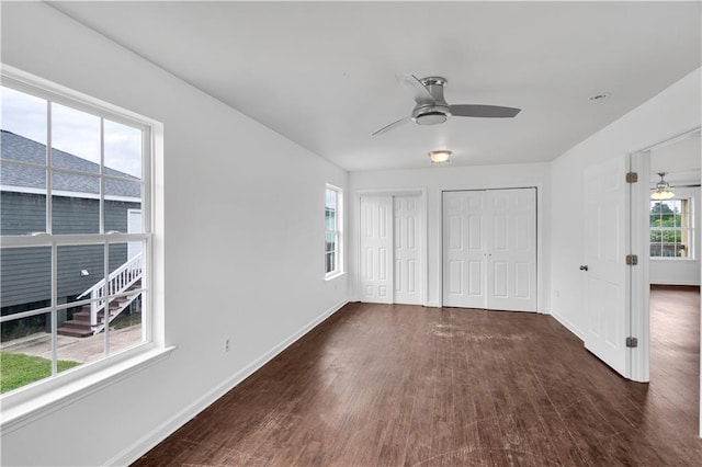 interior space with a ceiling fan, dark wood finished floors, baseboards, and two closets