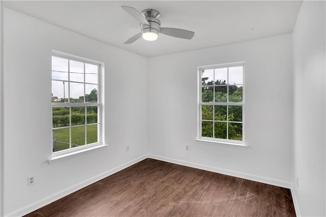 empty room featuring dark wood finished floors, baseboards, and ceiling fan