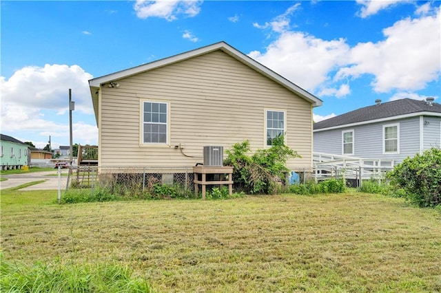 rear view of house with central AC and a lawn