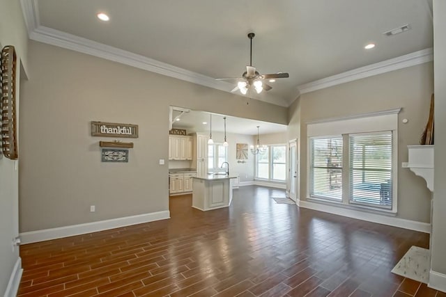 unfurnished living room with ceiling fan with notable chandelier, dark wood-type flooring, ornamental molding, and baseboards