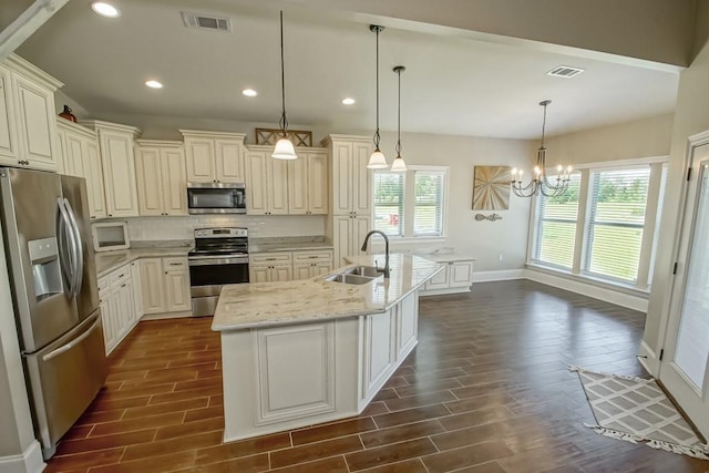 kitchen with a kitchen island with sink, a sink, visible vents, appliances with stainless steel finishes, and pendant lighting