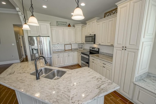 kitchen featuring an island with sink, appliances with stainless steel finishes, hanging light fixtures, light stone countertops, and a sink