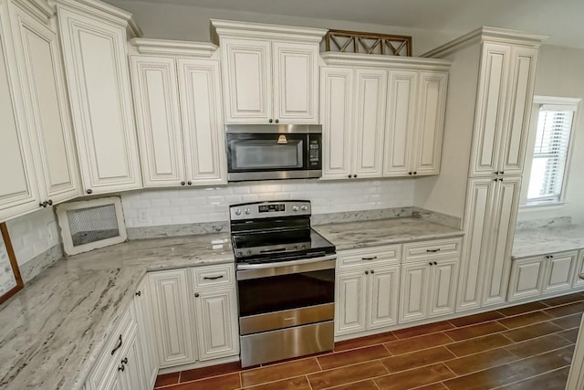 kitchen with stainless steel appliances, light stone counters, wood finish floors, and decorative backsplash