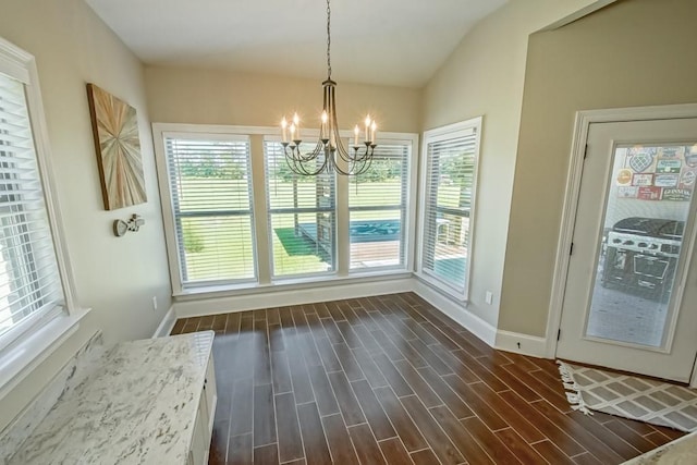 unfurnished dining area with wood tiled floor, a healthy amount of sunlight, lofted ceiling, and an inviting chandelier