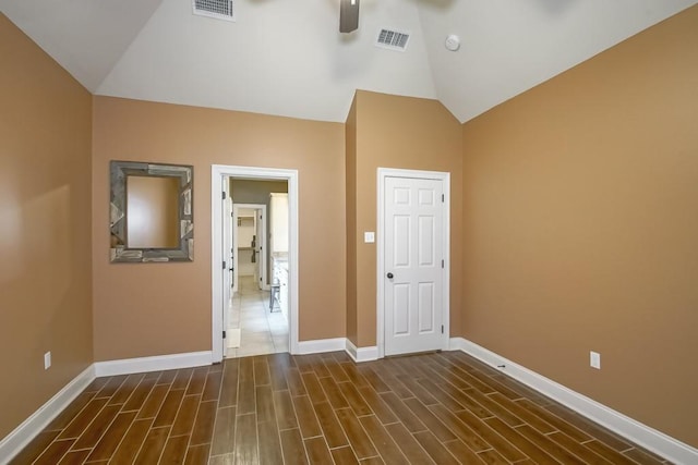 empty room with lofted ceiling, visible vents, and wood tiled floor