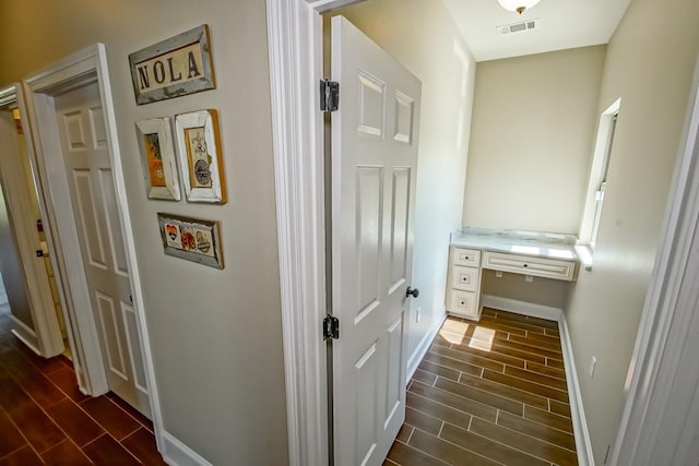 hallway featuring wood finish floors, visible vents, and baseboards