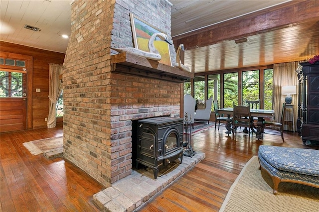 living room with hardwood / wood-style flooring, a wood stove, wooden ceiling, and wood walls