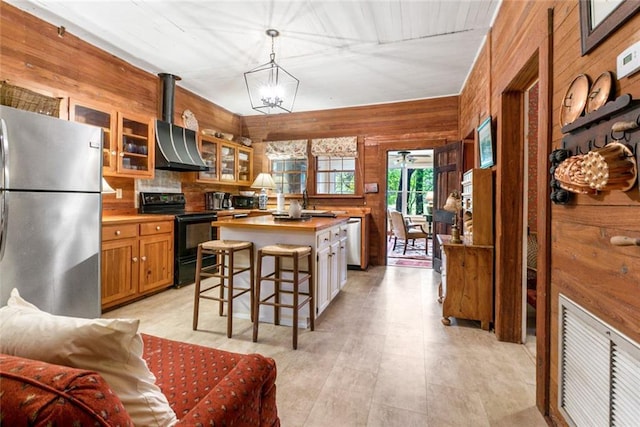 kitchen with appliances with stainless steel finishes, wood walls, a center island, and pendant lighting