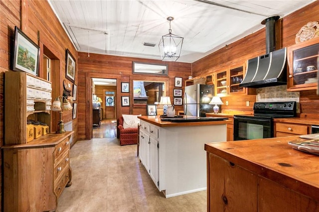 kitchen featuring wooden walls, stainless steel fridge, ventilation hood, black electric range, and white cabinetry