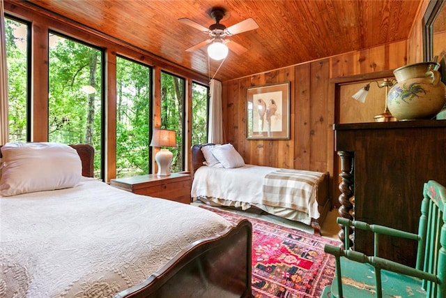 bedroom featuring multiple windows, wooden walls, wooden ceiling, and ceiling fan