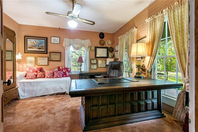 office featuring wood walls, carpet flooring, and ceiling fan