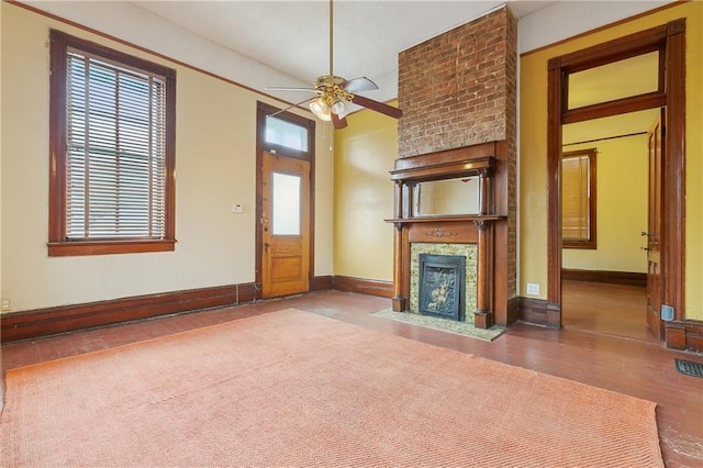 unfurnished living room featuring hardwood / wood-style flooring, ceiling fan, and a fireplace