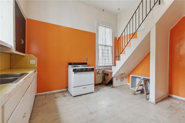 kitchen with white cabinets, sink, and white gas stove