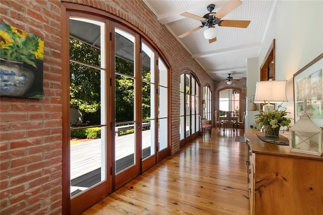 doorway to outside featuring beam ceiling, ceiling fan, french doors, light hardwood / wood-style flooring, and brick wall