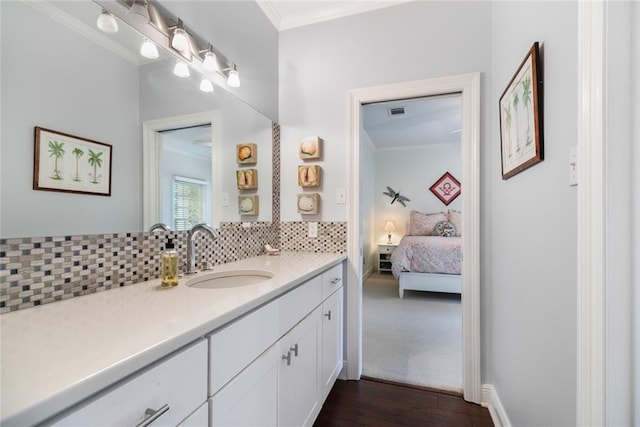 bathroom featuring hardwood / wood-style flooring, vanity, crown molding, and tasteful backsplash