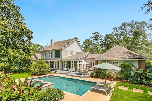 back of house with a swimming pool with hot tub, french doors, and a patio area