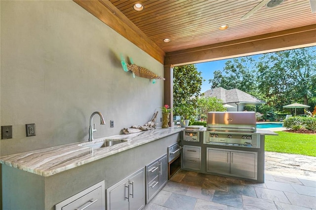 view of patio / terrace with sink, ceiling fan, a pool, area for grilling, and exterior kitchen