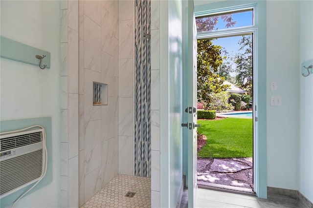 bathroom featuring a tile shower and a wall unit AC