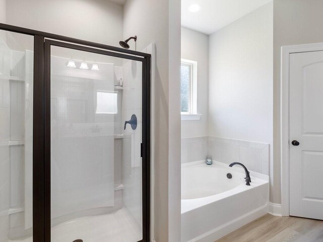 full bath with a bath, a shower stall, and wood finished floors