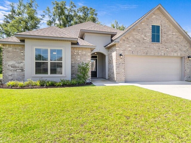 view of front of property with a garage, concrete driveway, brick siding, and a front yard