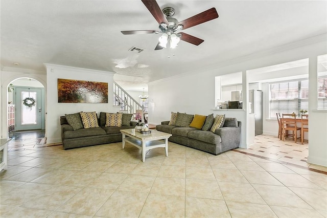 tiled living room with ceiling fan and crown molding