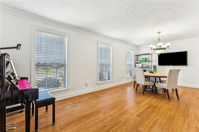 dining room with a notable chandelier, crown molding, and light hardwood / wood-style flooring