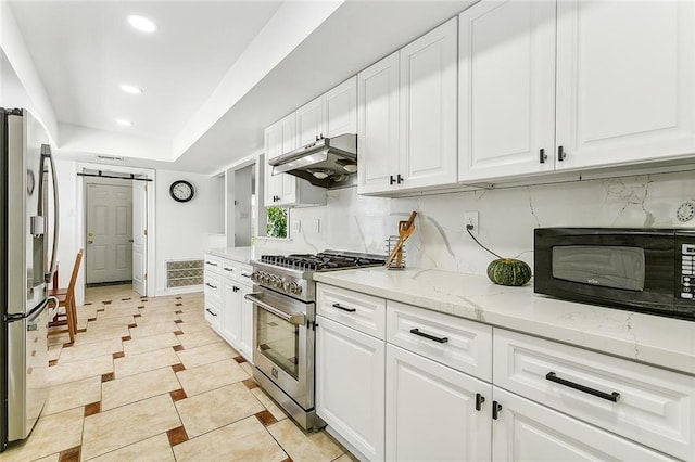 kitchen featuring decorative backsplash, appliances with stainless steel finishes, light stone counters, a barn door, and white cabinetry