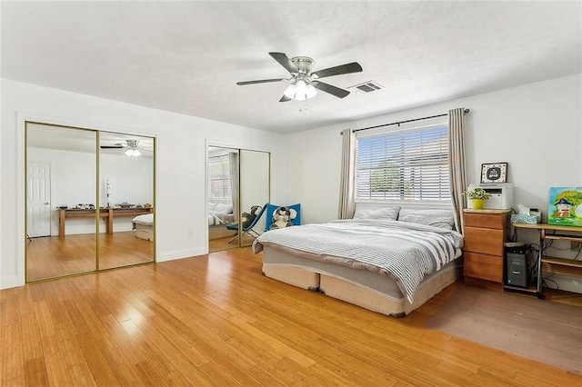 bedroom featuring ceiling fan, two closets, and light wood-type flooring