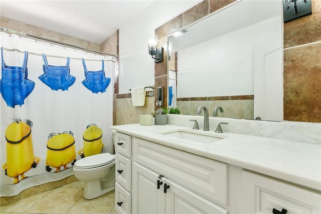 bathroom with toilet, vanity, tile patterned floors, and tile walls