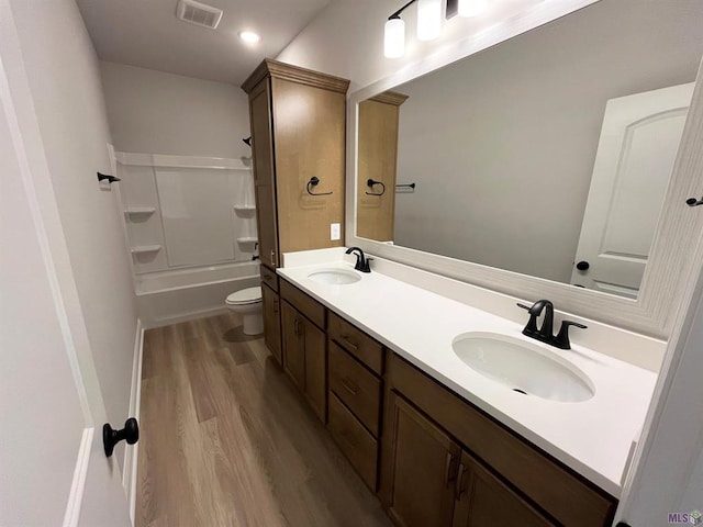 full bathroom featuring wood-type flooring, vanity, shower / bath combination, and toilet