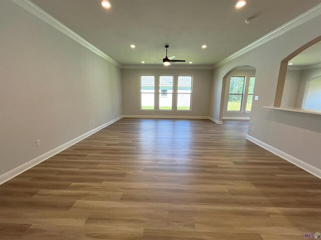 unfurnished living room featuring crown molding, arched walkways, baseboards, recessed lighting, and a ceiling fan