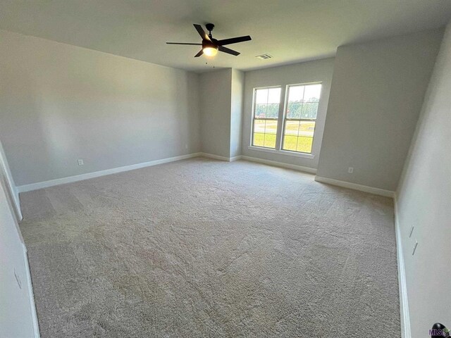 empty room featuring baseboards, visible vents, ceiling fan, and light colored carpet