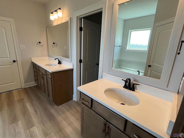 bathroom with wood-type flooring, a bath, and vanity