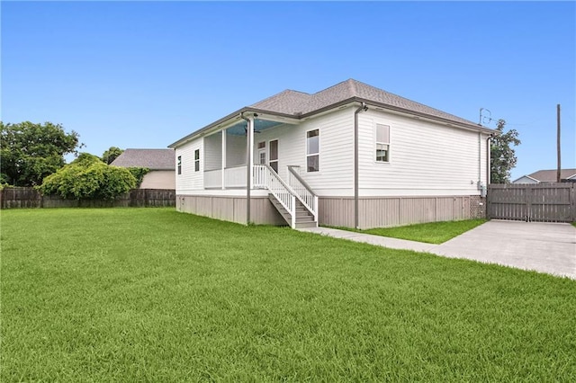 rear view of house featuring a porch and a yard