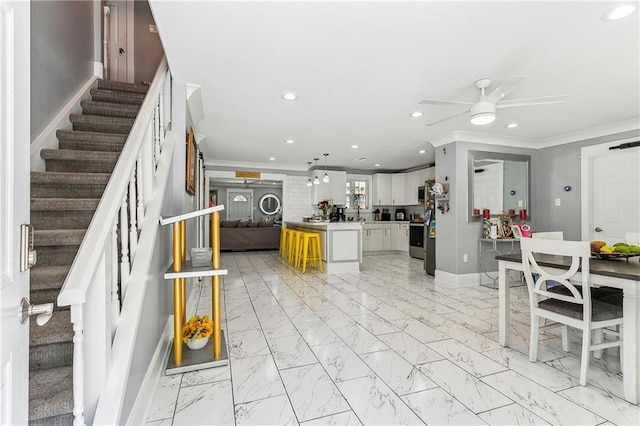 interior space featuring crown molding, ceiling fan, a kitchen island, and white cabinets