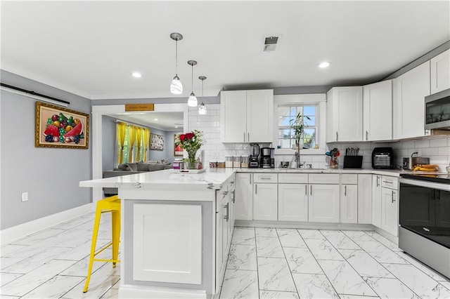 kitchen featuring tasteful backsplash, white cabinets, a breakfast bar, and stainless steel appliances