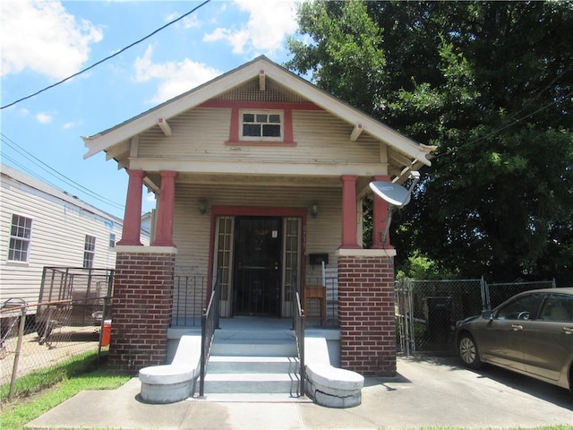 8719 Fig St, New Orleans, LA 70118 - view of front of property with fence, a gate, a porch, and brick siding