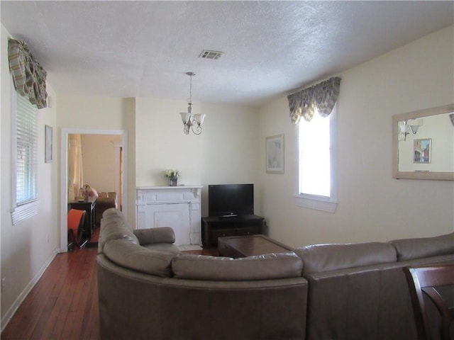8719 Fig St, New Orleans, LA 70118 - living area featuring a notable chandelier, a textured ceiling, dark wood finished floors, baseboards, and visible vents