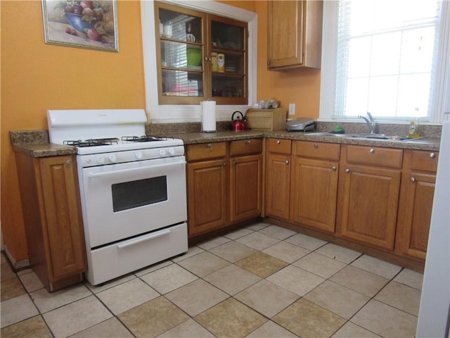 8719 Fig St, New Orleans, LA 70118 - kitchen with a sink, light tile patterned floors, gas range gas stove, and brown cabinets