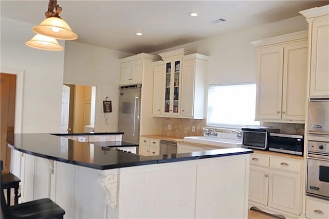 kitchen featuring appliances with stainless steel finishes, tasteful backsplash, pendant lighting, a kitchen island, and white cabinetry