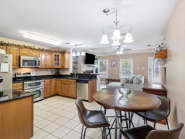 kitchen with ceiling fan with notable chandelier, stainless steel appliances, sink, light tile patterned floors, and decorative light fixtures