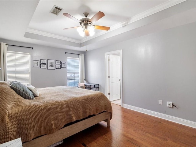 bedroom with a tray ceiling, ceiling fan, hardwood / wood-style floors, and ornamental molding