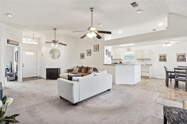 carpeted living room featuring high vaulted ceiling, a textured ceiling, and ceiling fan