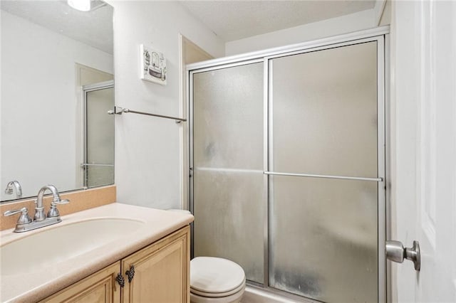 bathroom with a shower with door, vanity, a textured ceiling, and toilet